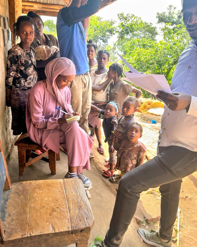 Research assistants Mathewos Bunaro (far right) and Nahil Gemechew (sitting in pink), interview households in the Gelta Dada Zone.