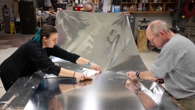 Fritz Bernstein, technical director, and Savannah Relos, assistant technical director, both in the Department of Performing and Media Arts in the College of Arts and Sciences, apply a reflective surface to a stage that will be installed in the Kiplinger Theater as part of the dance performance.