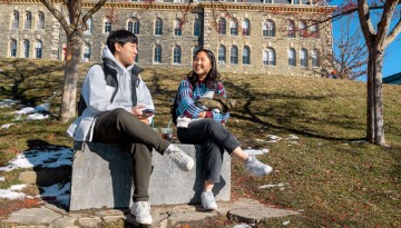 Two students sit on stone 