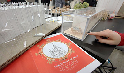 Lauren Gluck '12 points to a detail of an architectural model at a reception